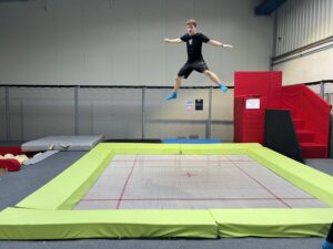 Uczeń pokazuje swoje umiejętności akrobatyczne na trampolinie.