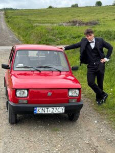 Uczeń fotografuje się przy samochodzie zdjęcie 1