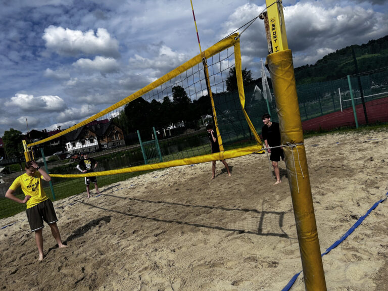 Skoncentrowani i skupieni chłopcy walczą na boisku do siatkówki plażowej o każdą piłkę.