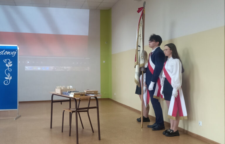 Dwoje dziewcząt i chłopak trzymają Sztandar Zespołu Szkół Zawodowych i Placówek