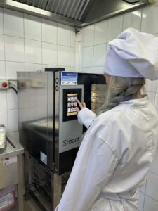 Kucharz w kitlu konfiguruje piec konwekcyjno-parowy