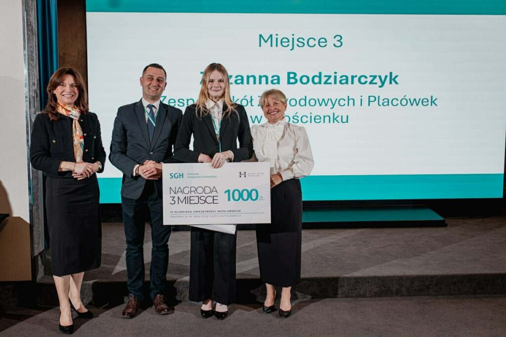 Grupa osób stojących przed planszą