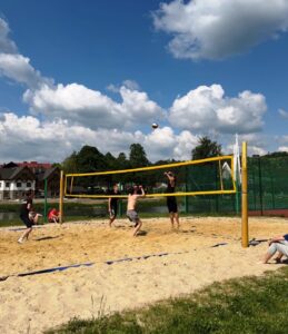 Skoncentrowani i skupieni chłopcy walczą na boisku do siatkówki plażowej o każdą piłkę.